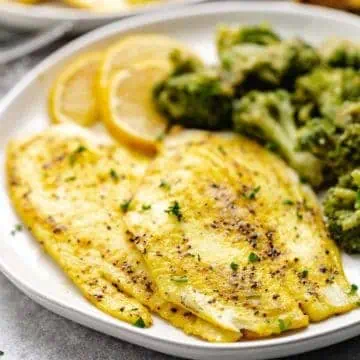 Close up view of lemon pepper fish fillets with steamed veggies.