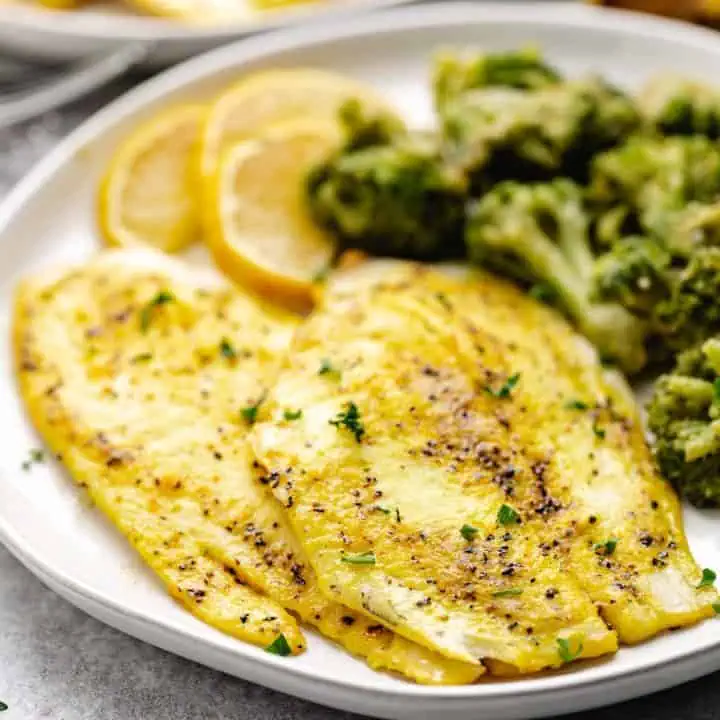 Close up view of lemon pepper fish fillets with steamed veggies.