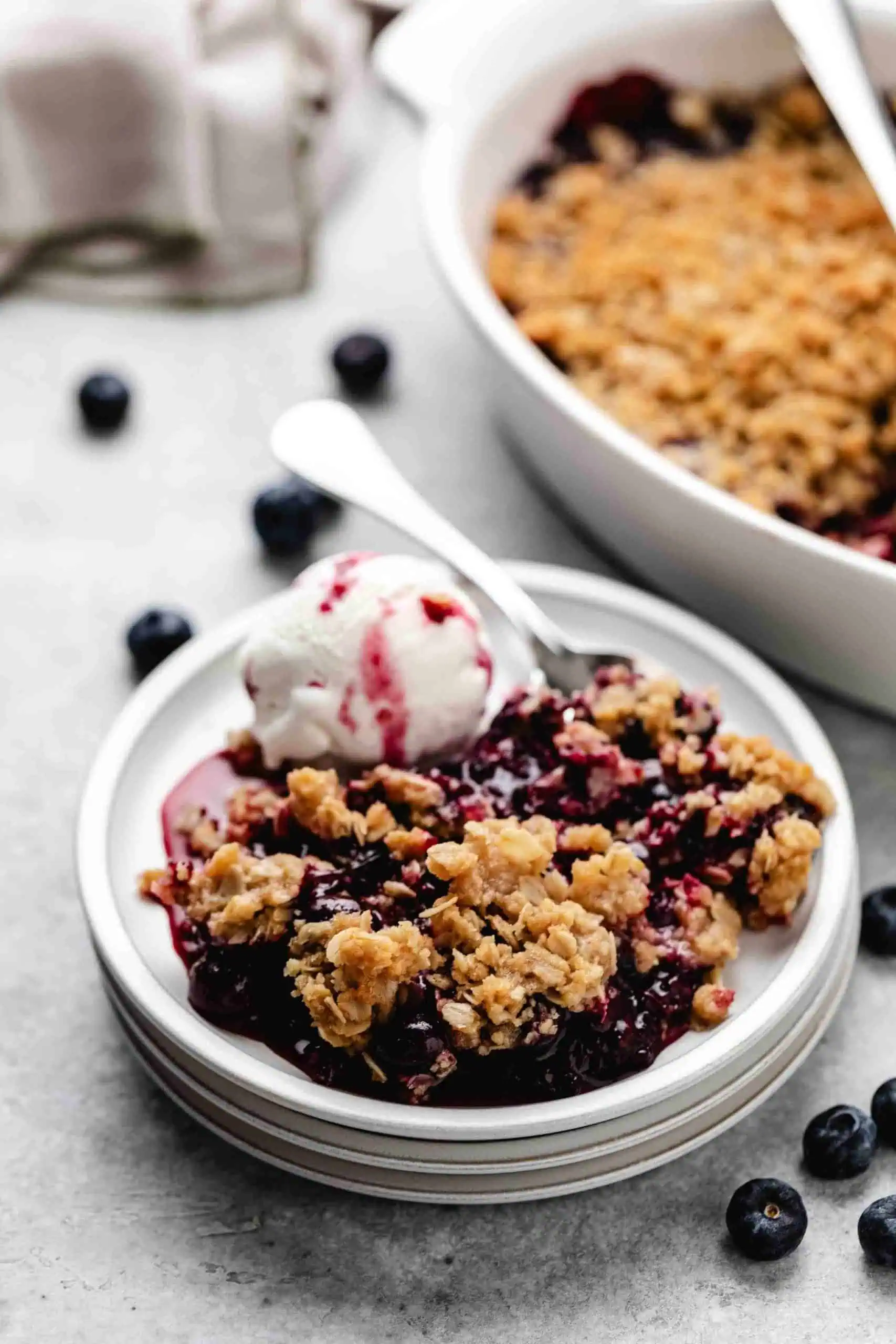 Blueberry crisp on a plate with vanilla ice cream.