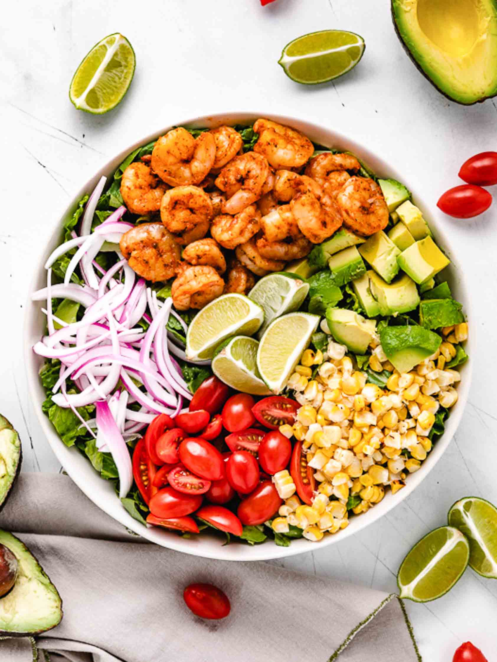Shrimp, tomatoes, corn, lettuce, avocado, and onions in a bowl.