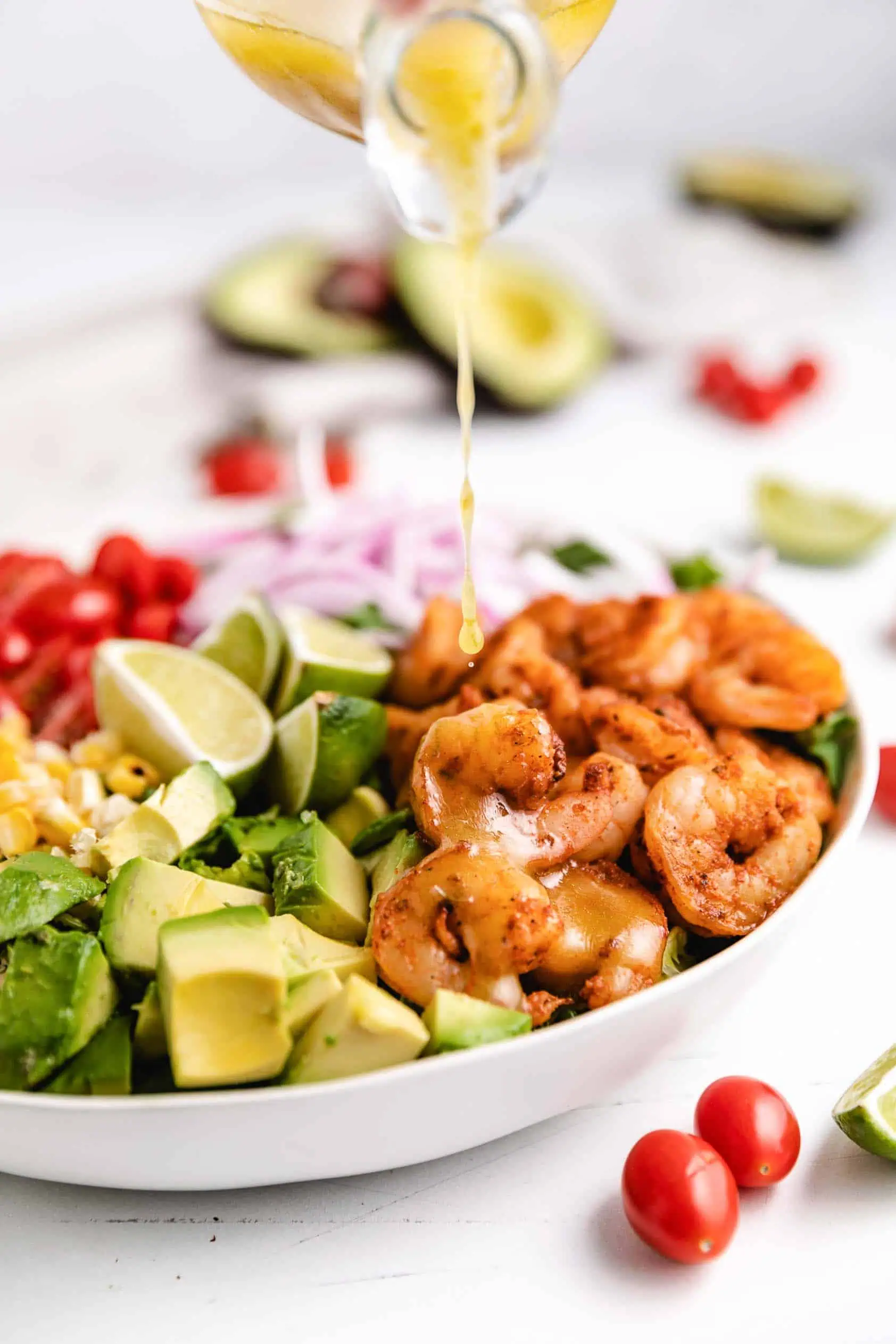 Dressing being poured onto grilled shrimp.