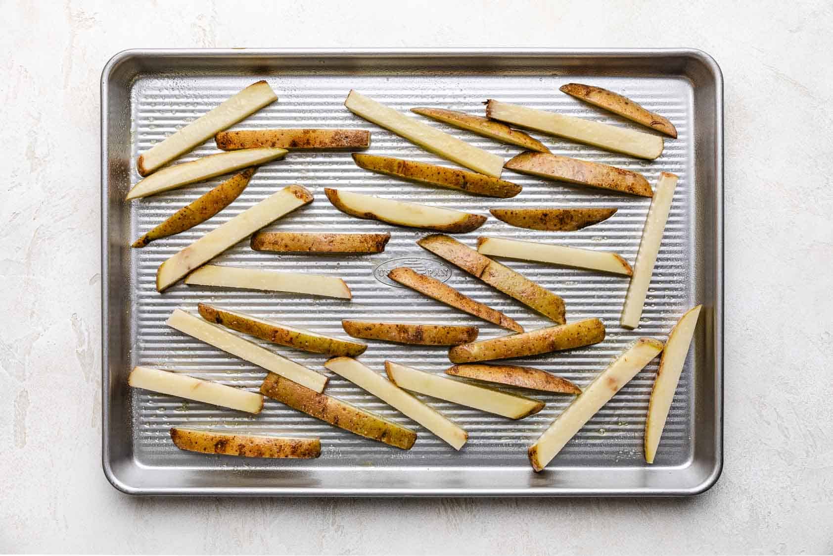 Large sheet pan filled with unbaked fries.