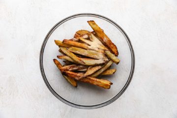 Baked fries with seasonings in a bowl.