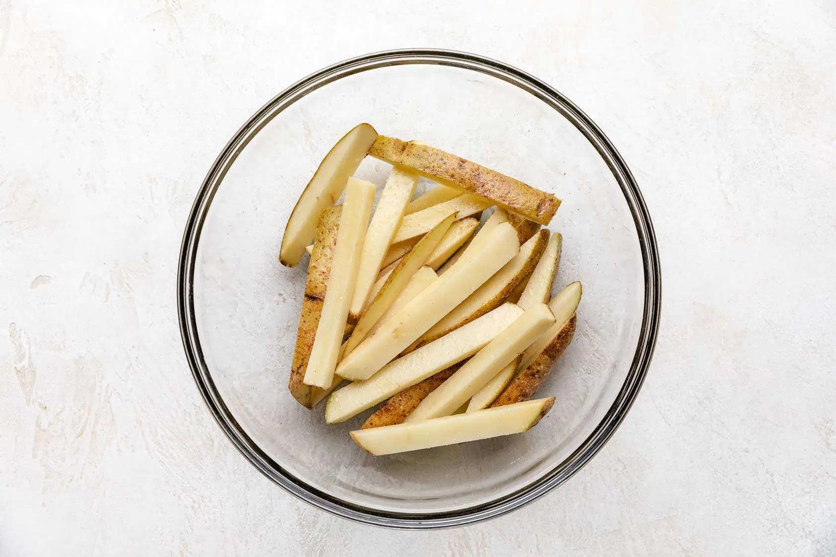 Sliced potatoes tossed with seasonings.