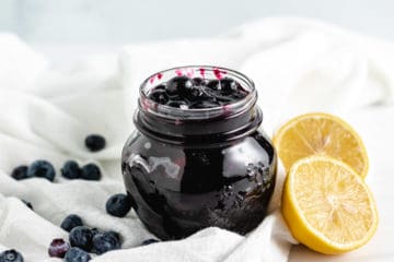 Side view of cooked blueberries in a jar.