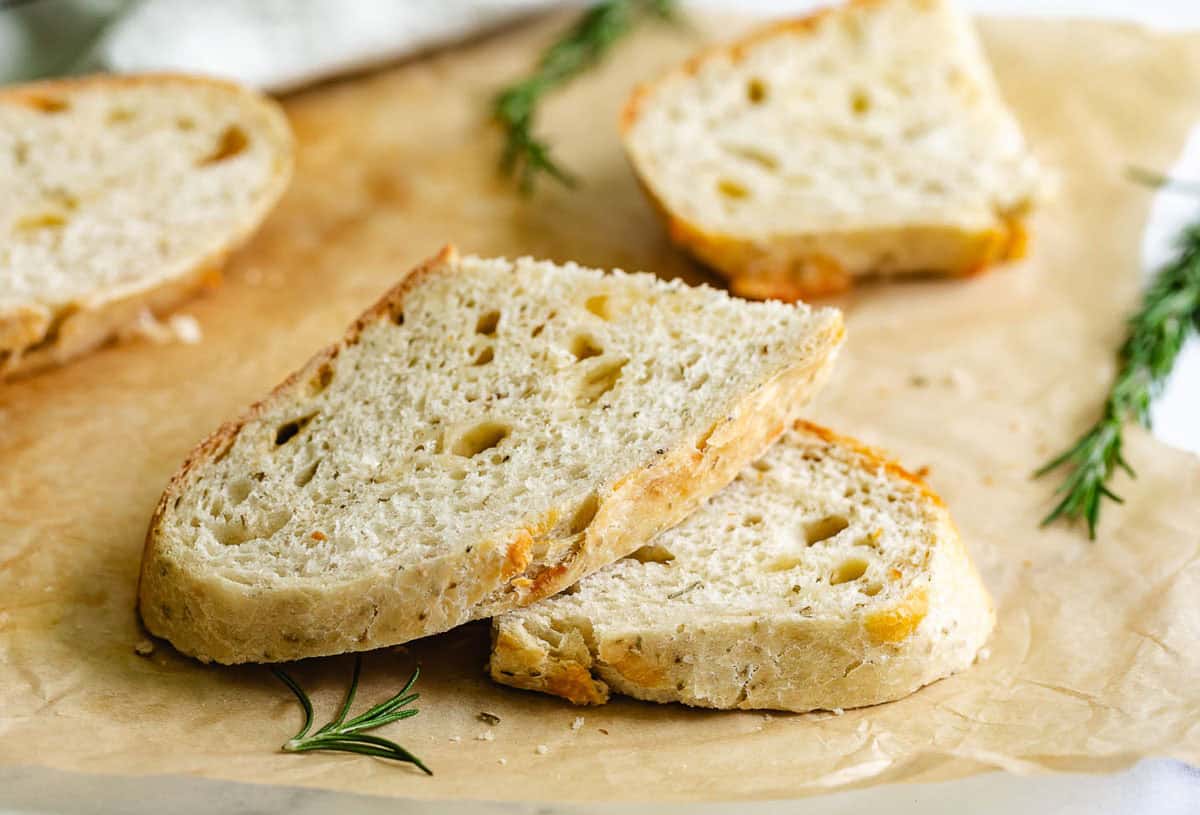 Slices of parmesan rosemary bread on parchment.