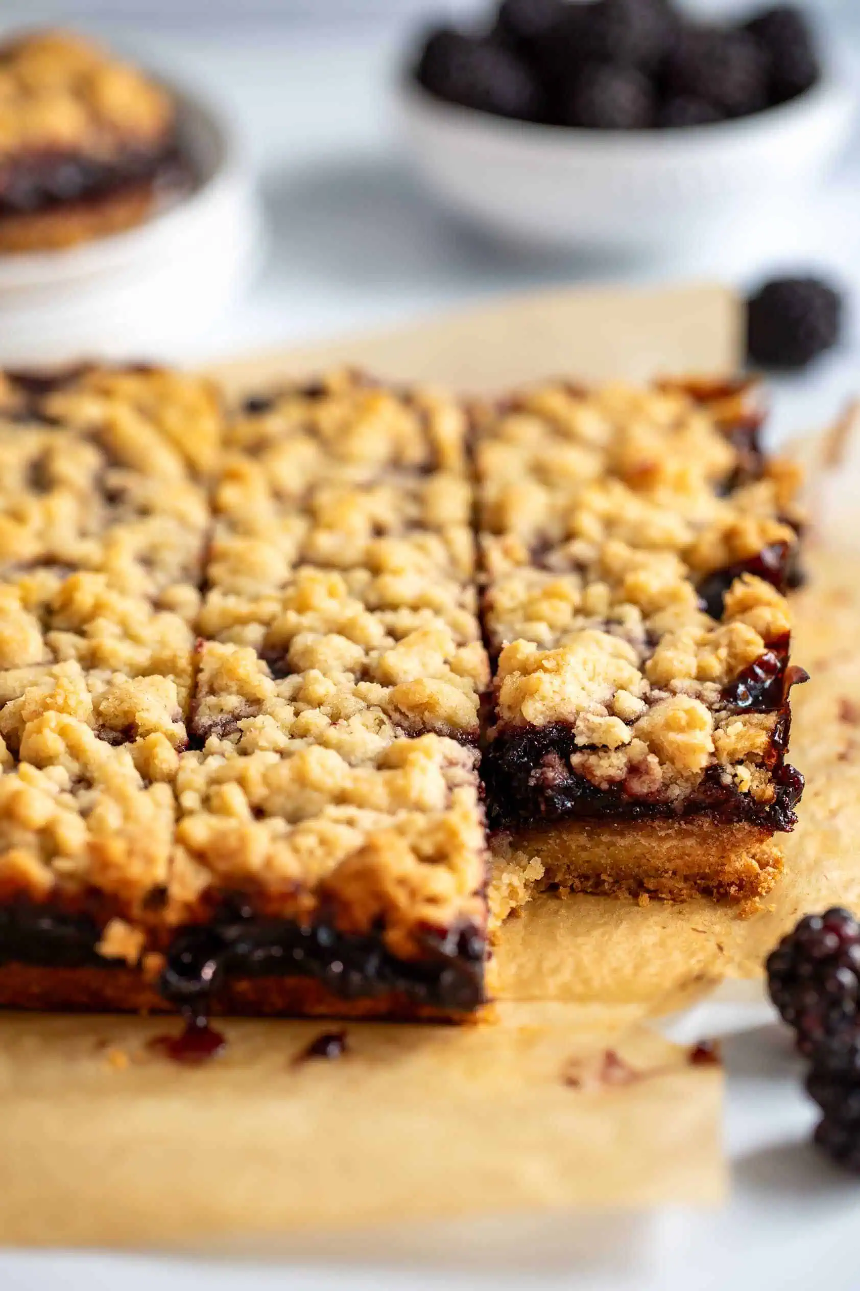 Batch of berry crumb bars on brown parchment.