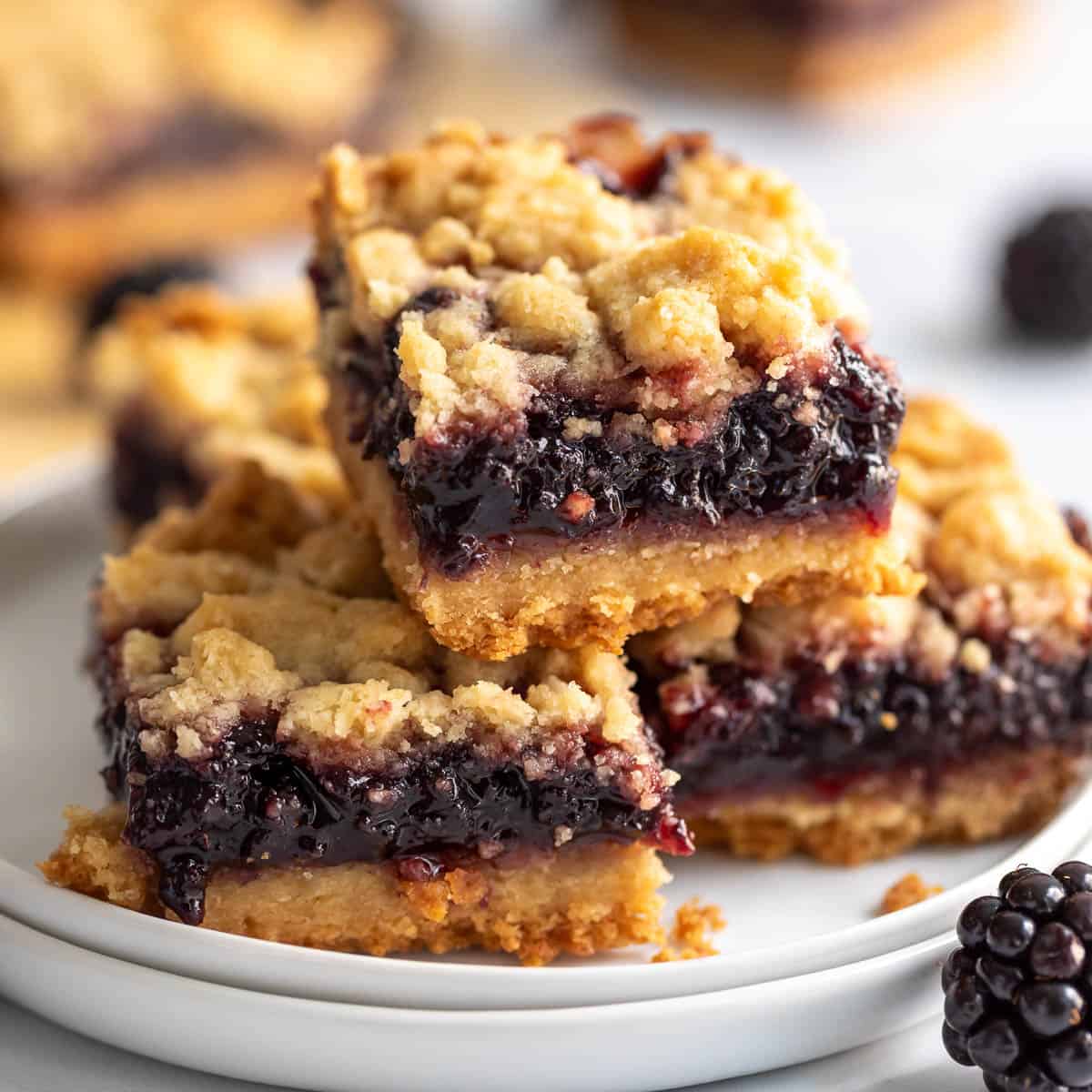 Stack of blackberry pie bars on two plates.