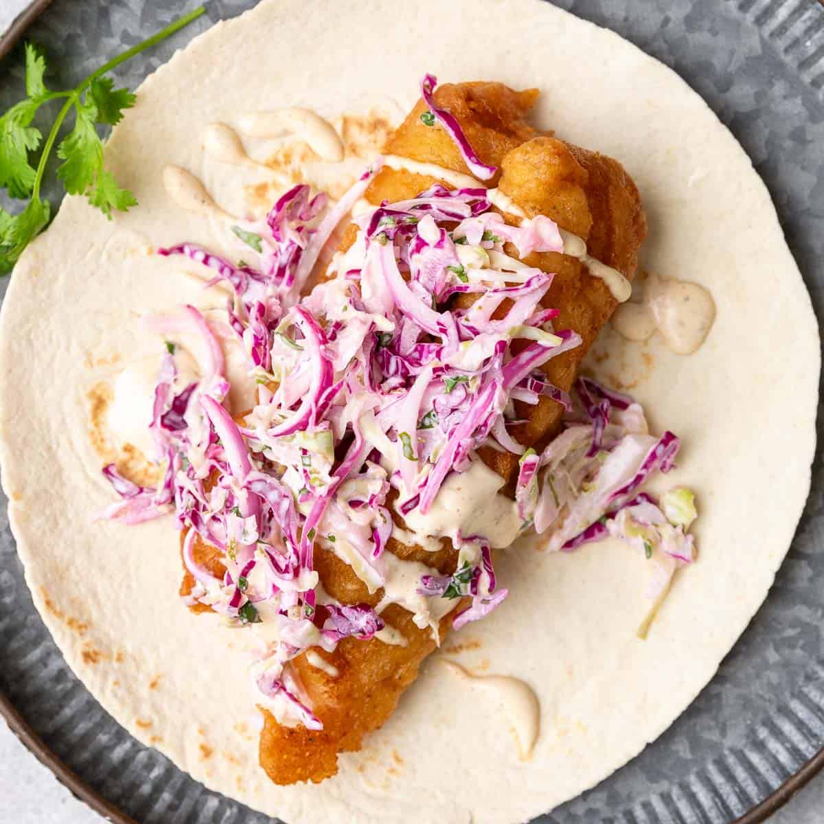 Close up view of an open faced beer battered cod taco.