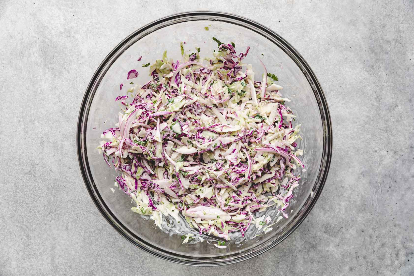 Lime dressing and cabbage mix combined in a bowl.