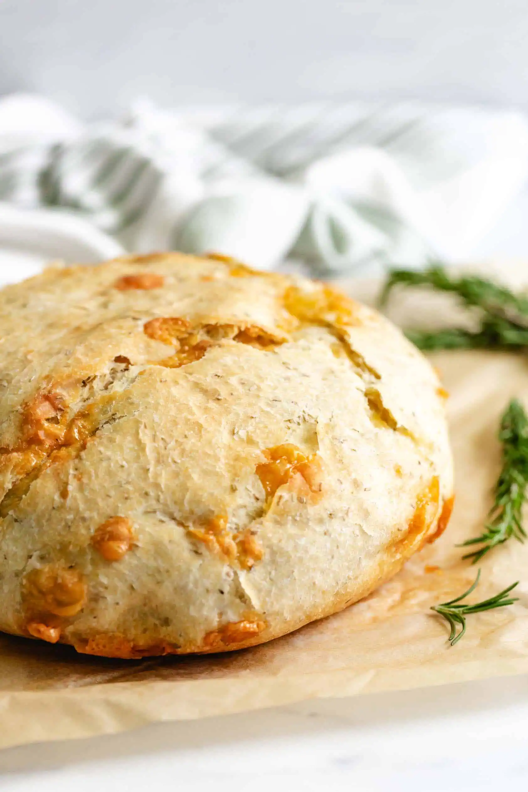 Loaf of parmesan rosemary bread on parchment paper.