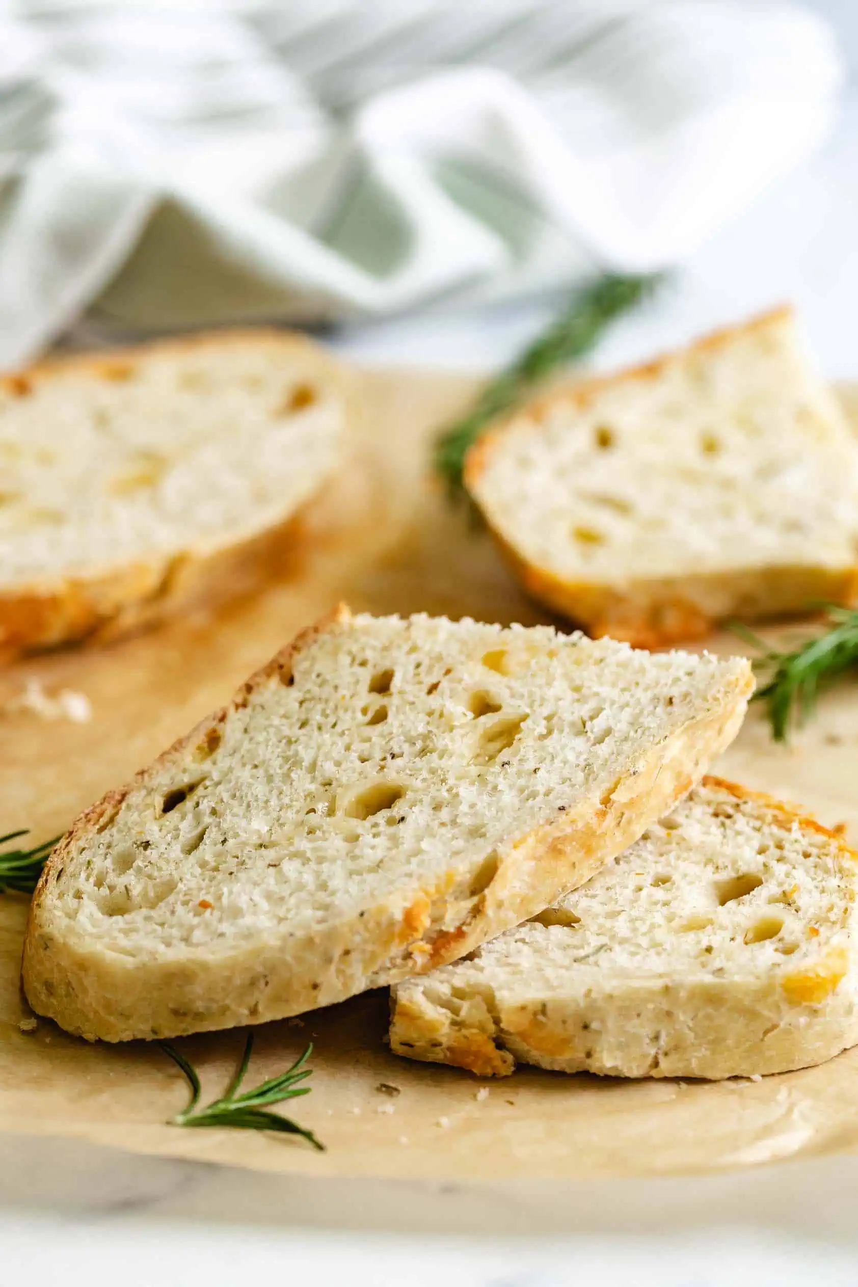 Stacks of rosemary parmesan bread next to fresh rosemary.