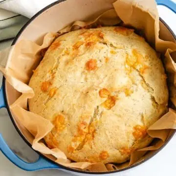 Loaf of bread on parchment in a pan.