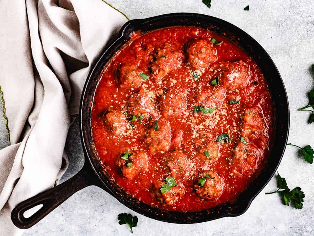 Top down view of a pan of baked meatballs in marinara.
