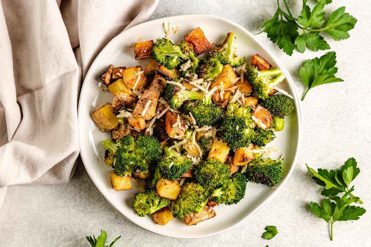 Roasted potatoes with broccoli and cheese on a white plate.