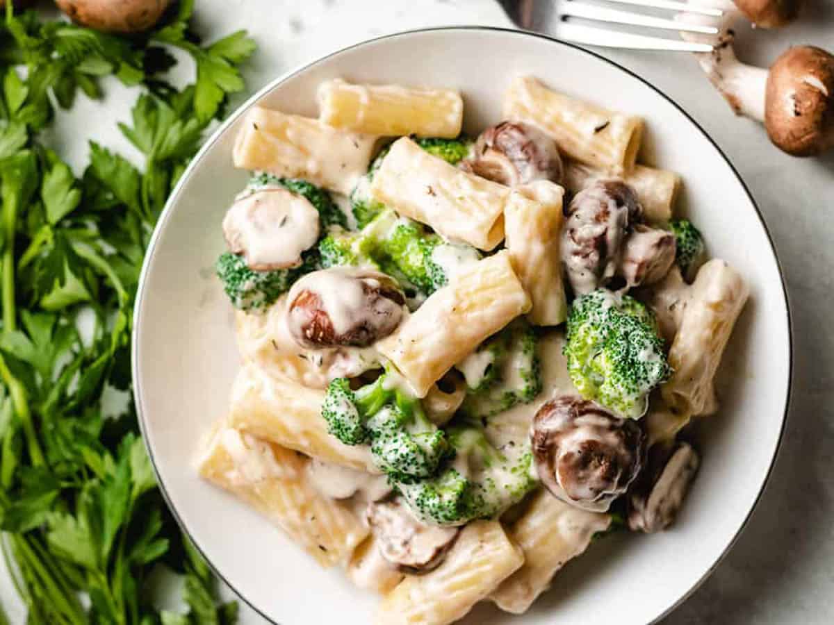 Mushroom broccoli pasta in a white dish.