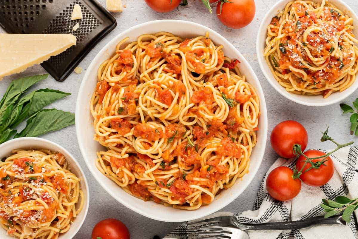 Tomato basil pasta in several white bowls.