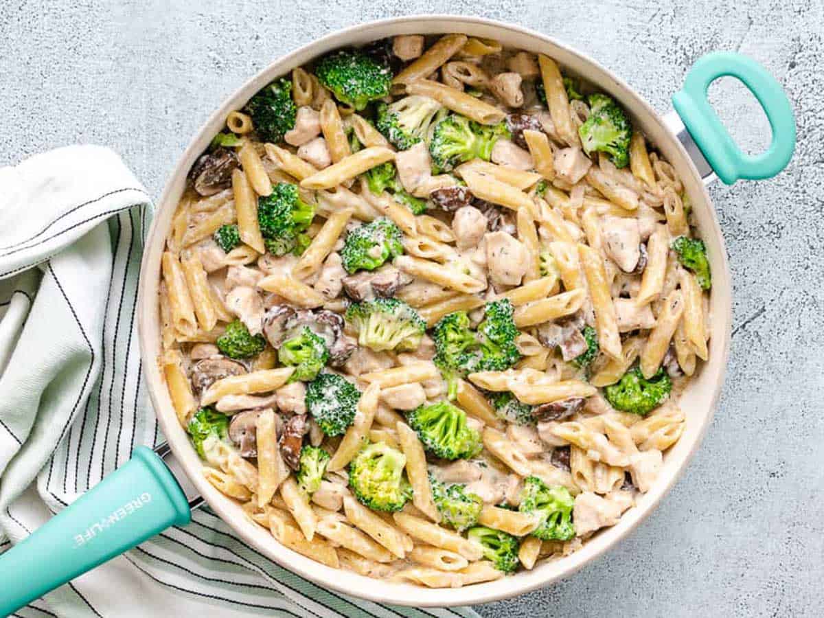 Chicken mushroom broccoli pasta in a blue green pan.