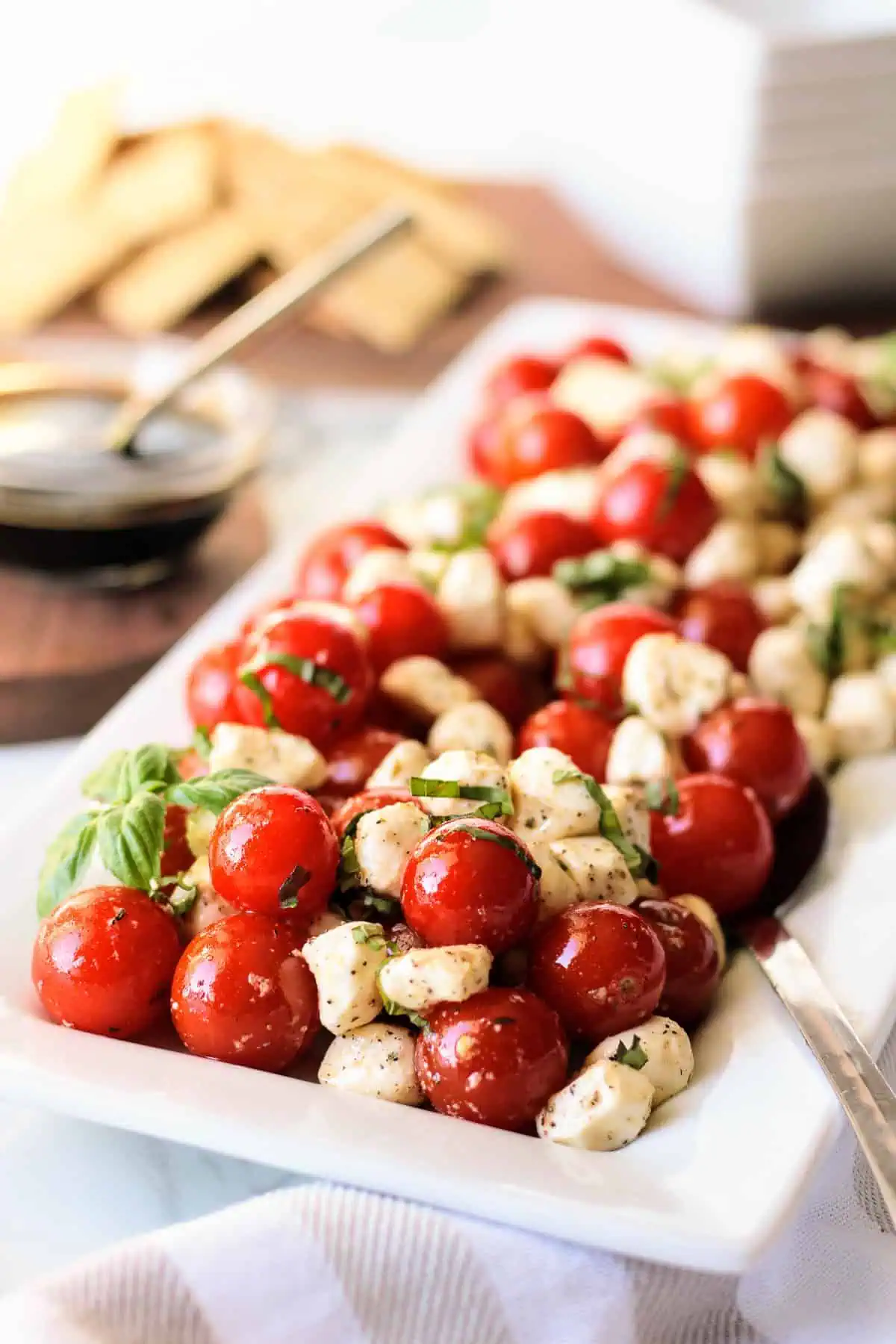 Caprese salad with basil on a rectangular plate.