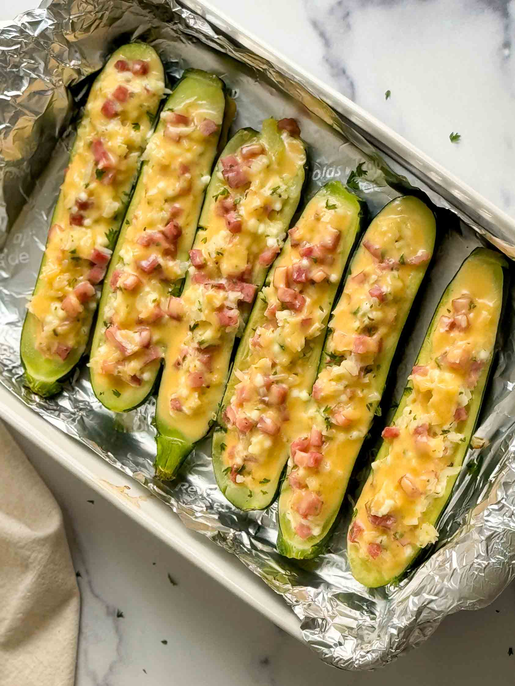 Top down view of cheesy zucchini boats in a dish.