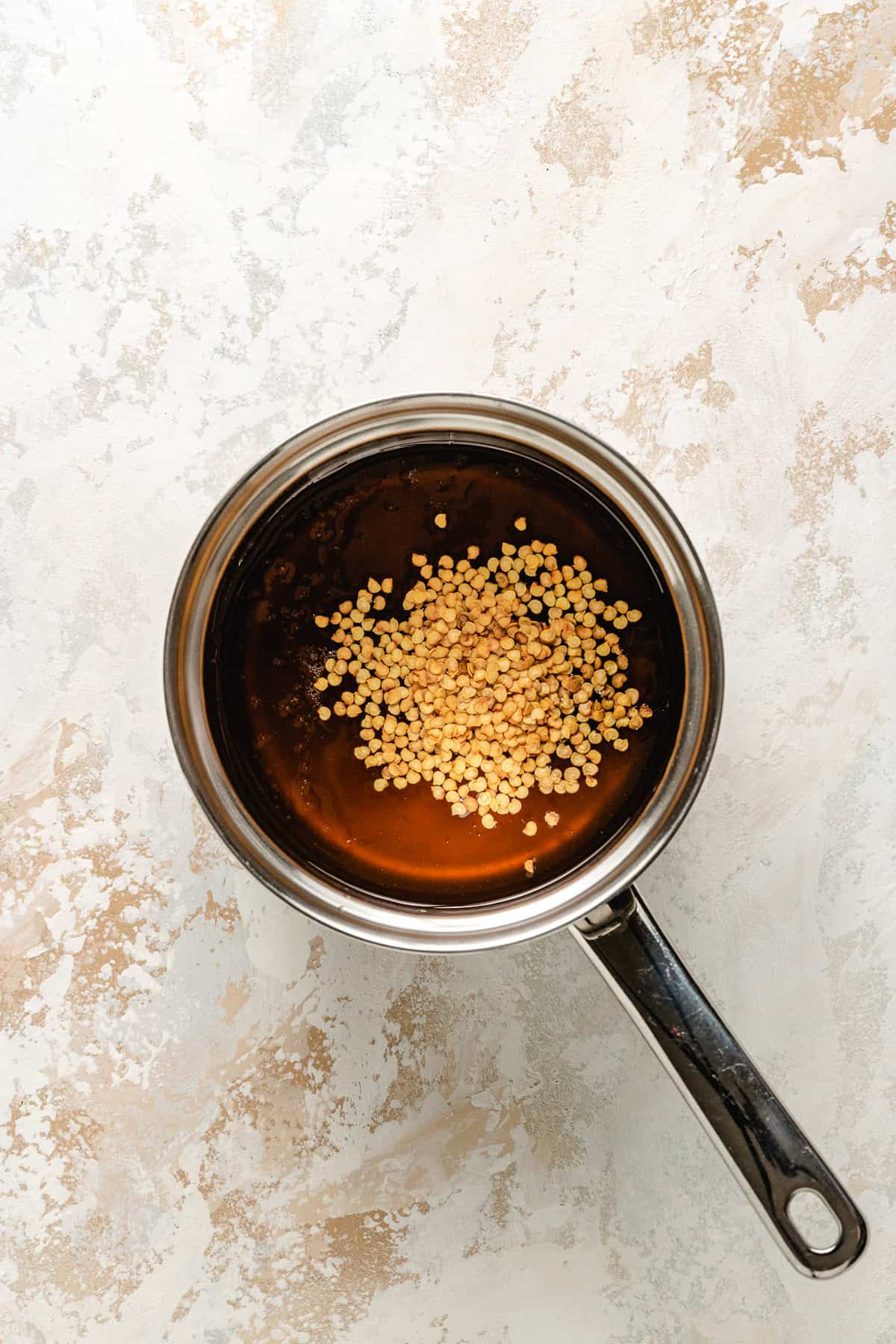 Red chili flakes added to a pan of honey.