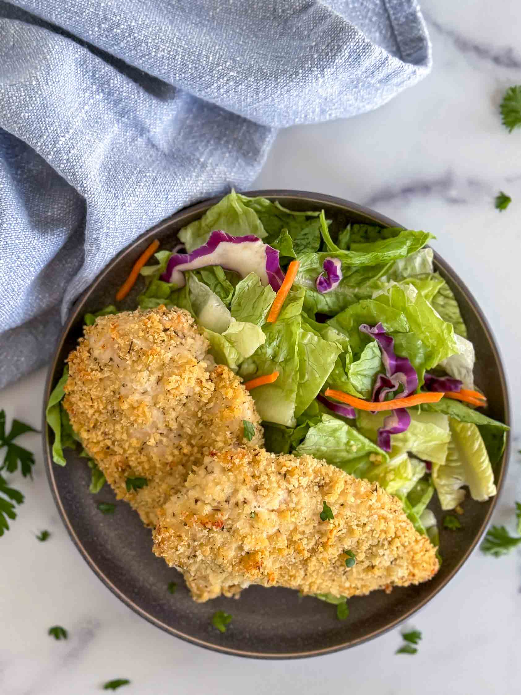 Two breaded chicken breasts on a plate.