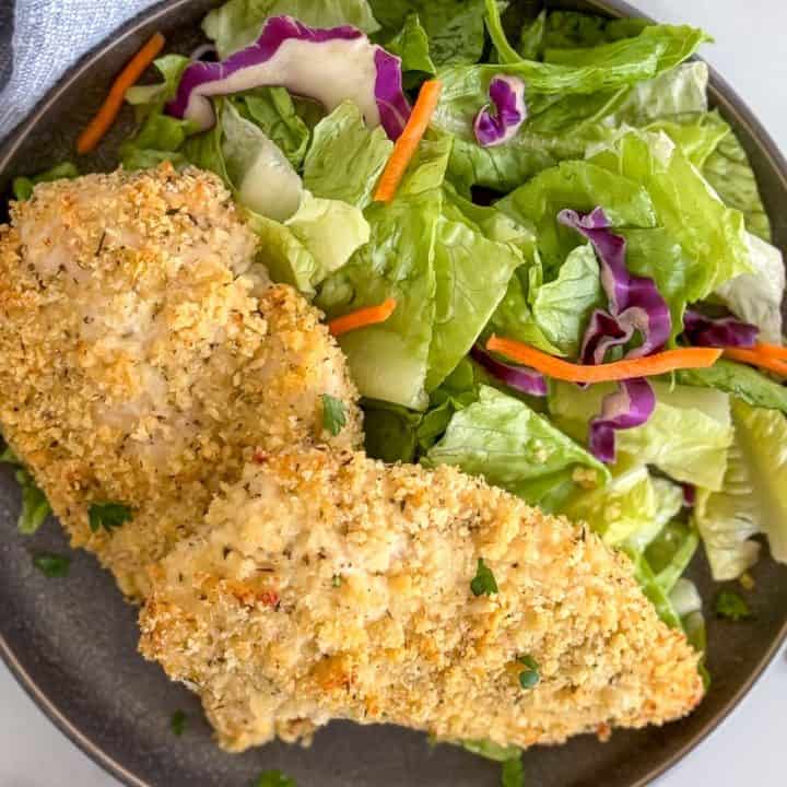 Two pieces of panko chicken on gray plates.