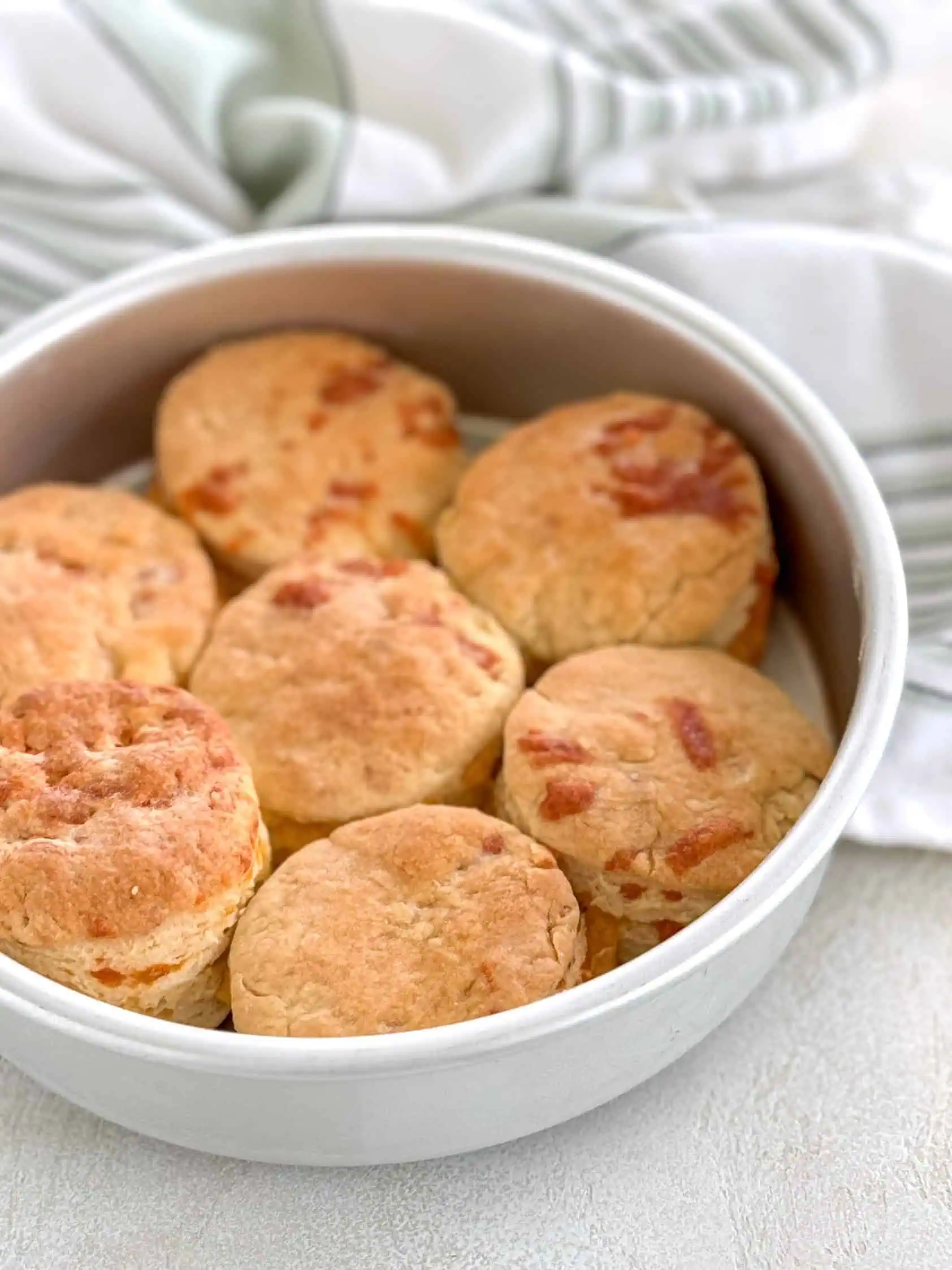 Freshly baked biscuits in a round baking pan, ready to be served.