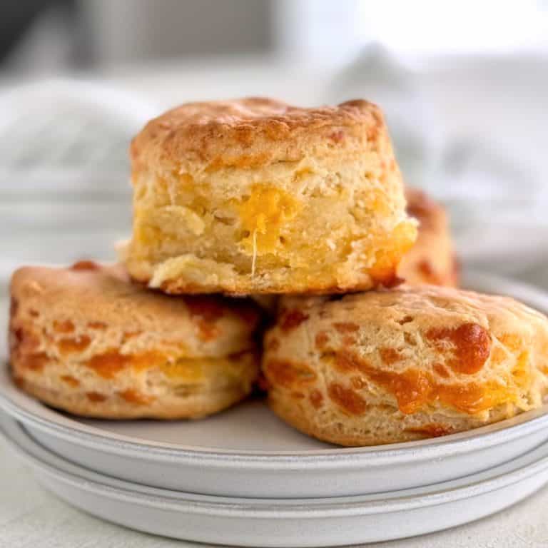 Close-up of buttery biscuits with melted cheese on a white plate.