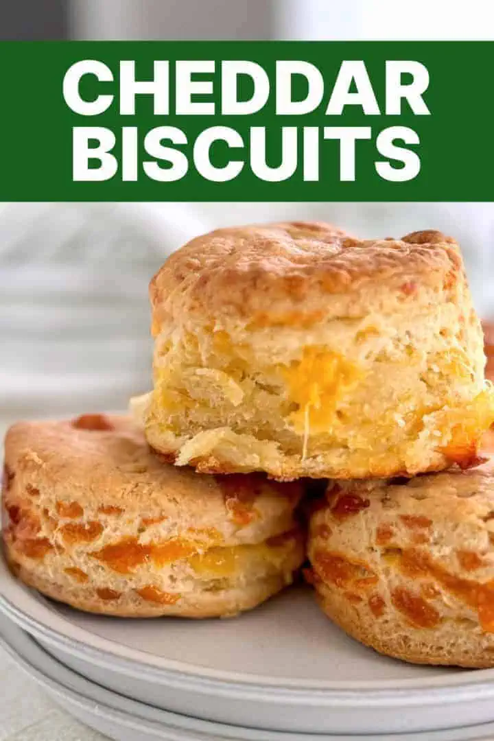 A plate of warm, homemade cheddar biscuits with a focus on the melty cheese inside.