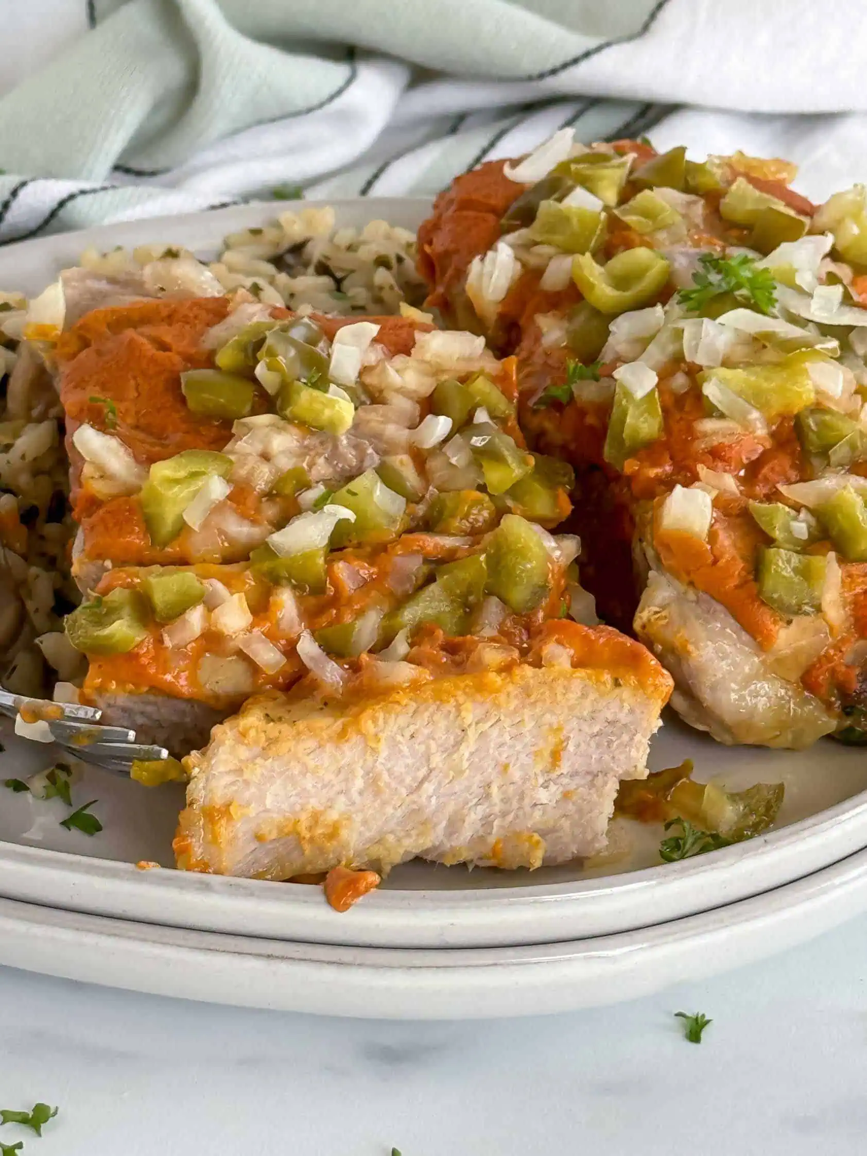 Sliced smothered pork chop served with diced peppers and onions.