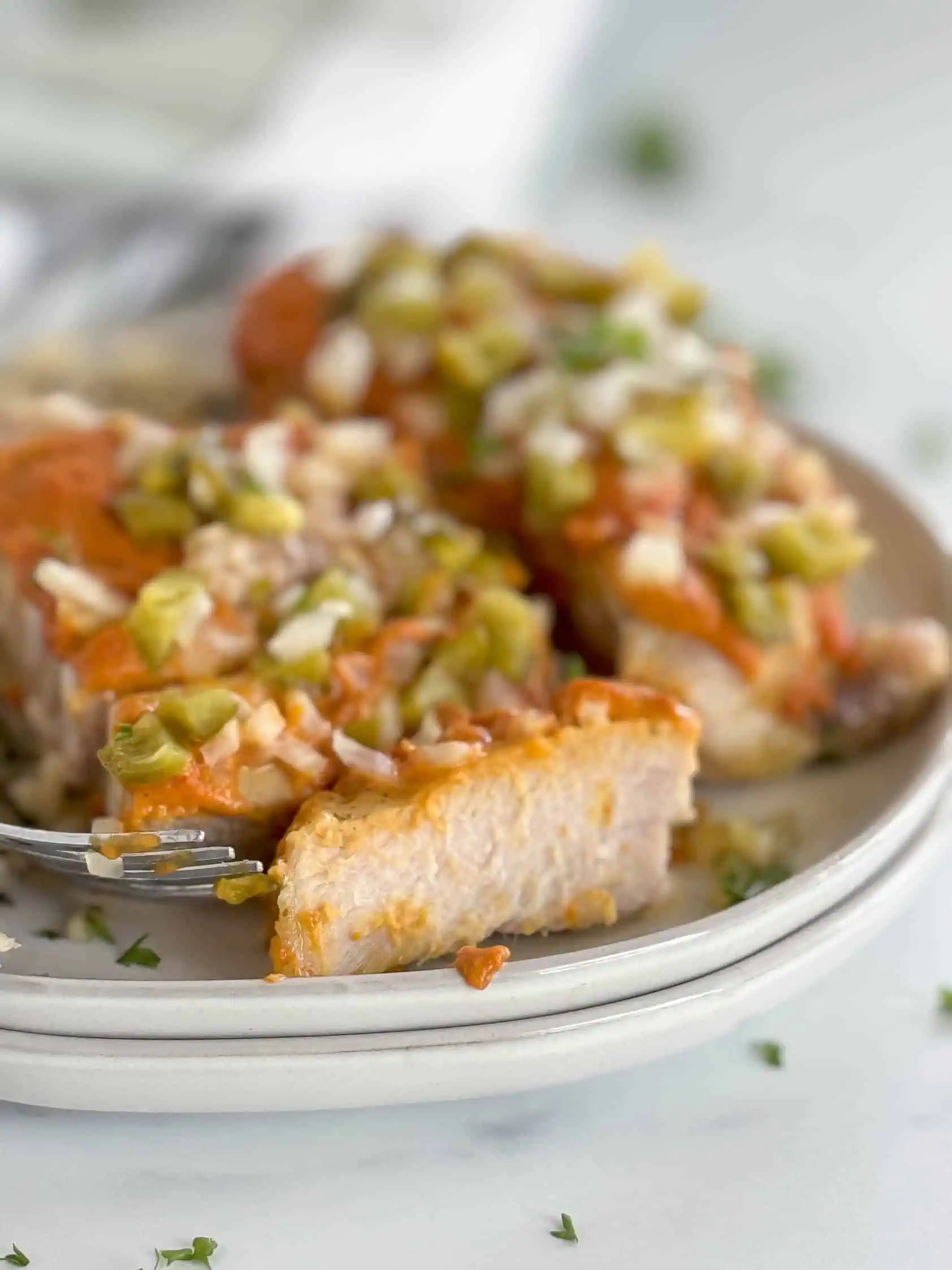 Juicy pork chop with sweet and savory toppings on a gray plate.