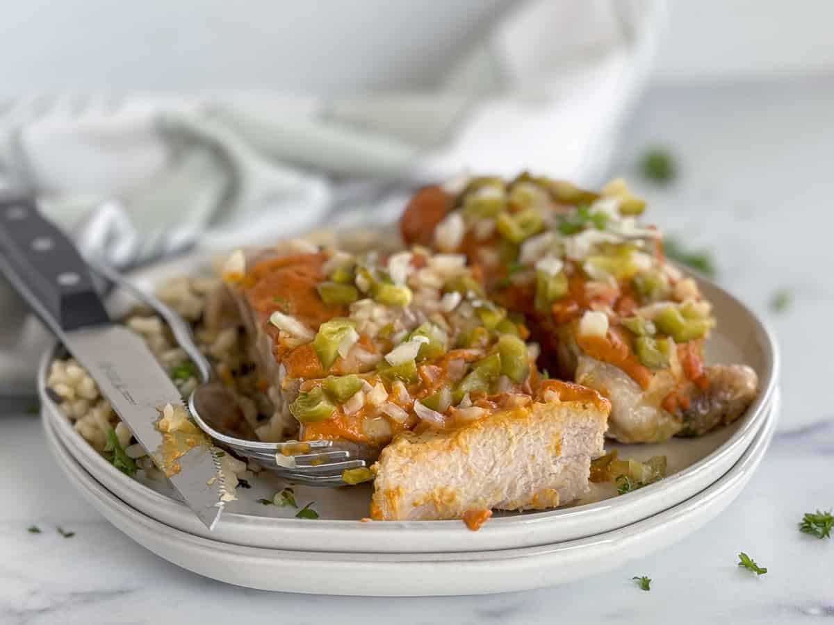 Delicious smothered pork chop with a savory glaze and vegetable topping.