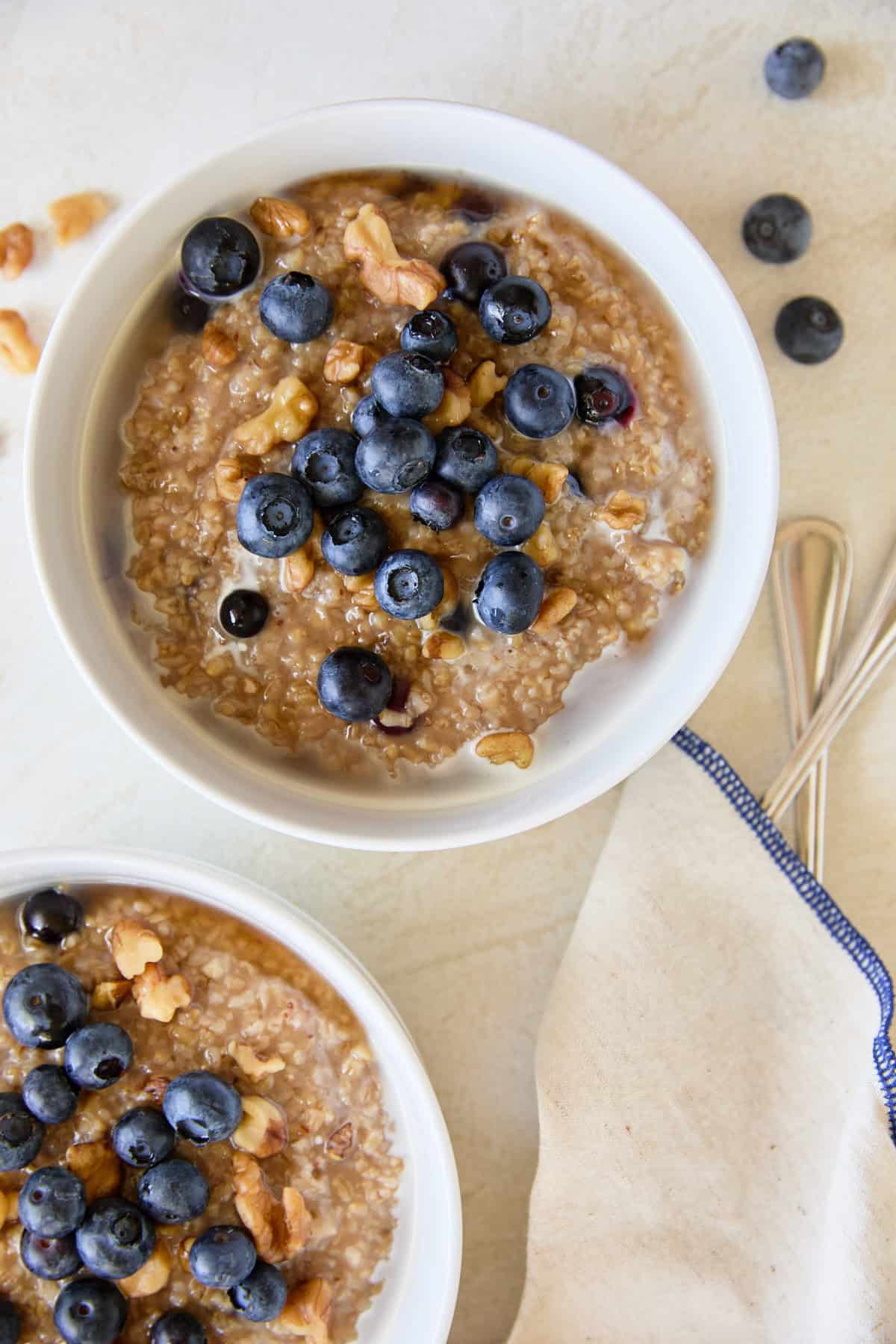 Top-down view of two bowls of blueberry steel cut oats, each topped with fresh blueberries and walnuts.