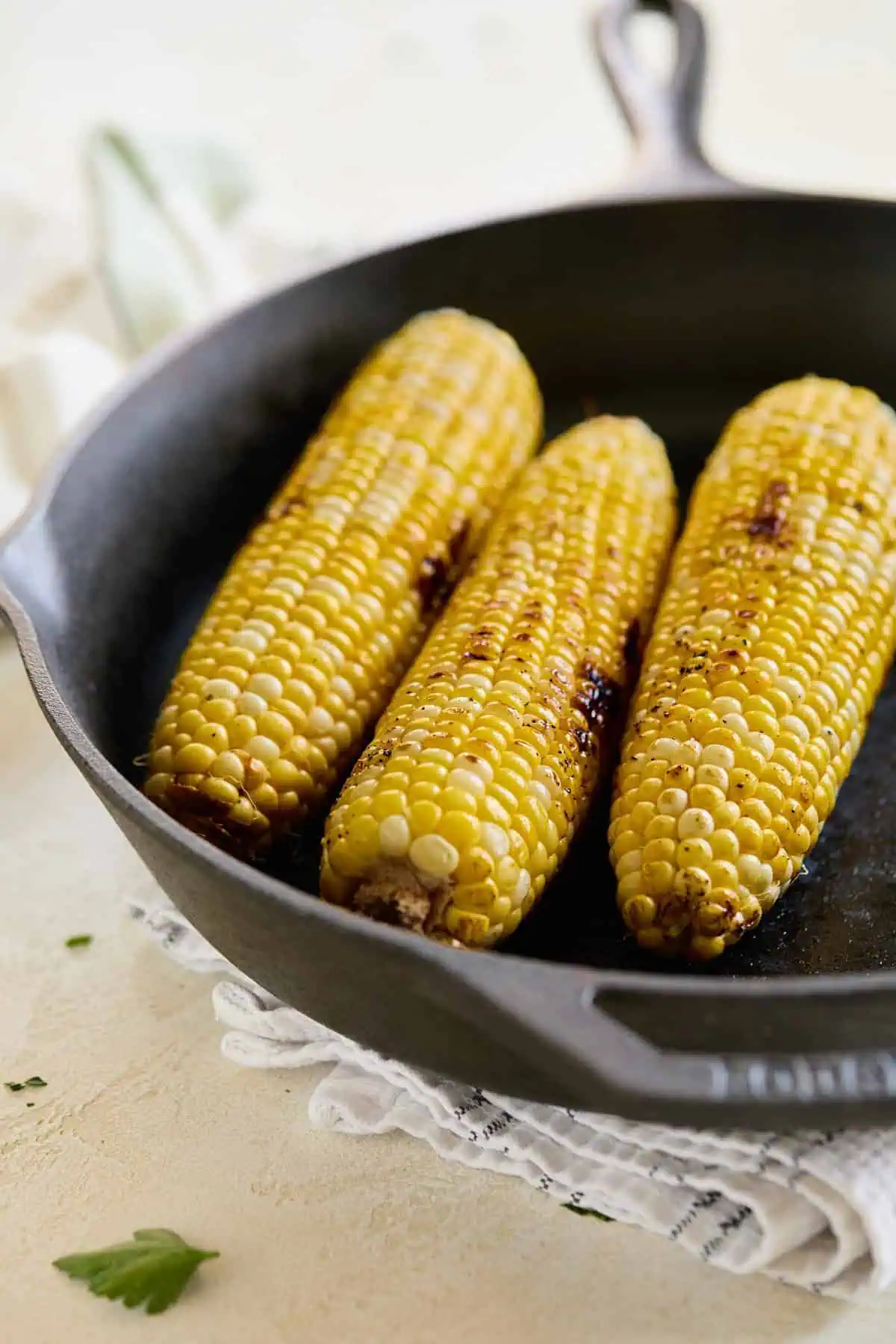 Grilled corn on the cob in a cast-iron skillet, slightly charred to enhance sweetness.