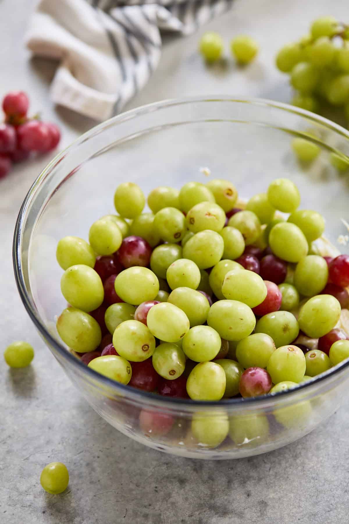 Fresh green and red seedless grapes in a glass bowl.