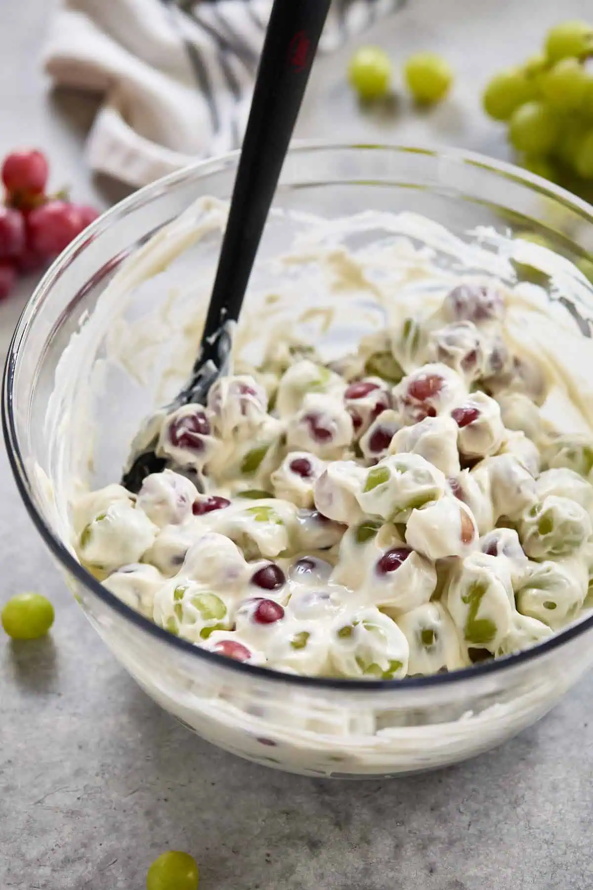 Grapes mixed with a creamy dressing in a glass bowl.