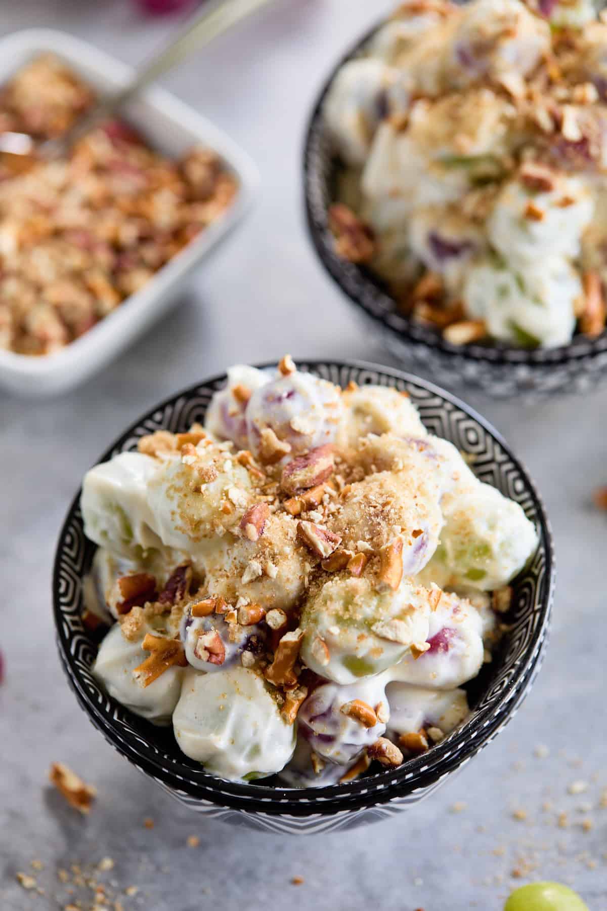 Close-up of grape salad with a crunchy topping in a black and white bowl.