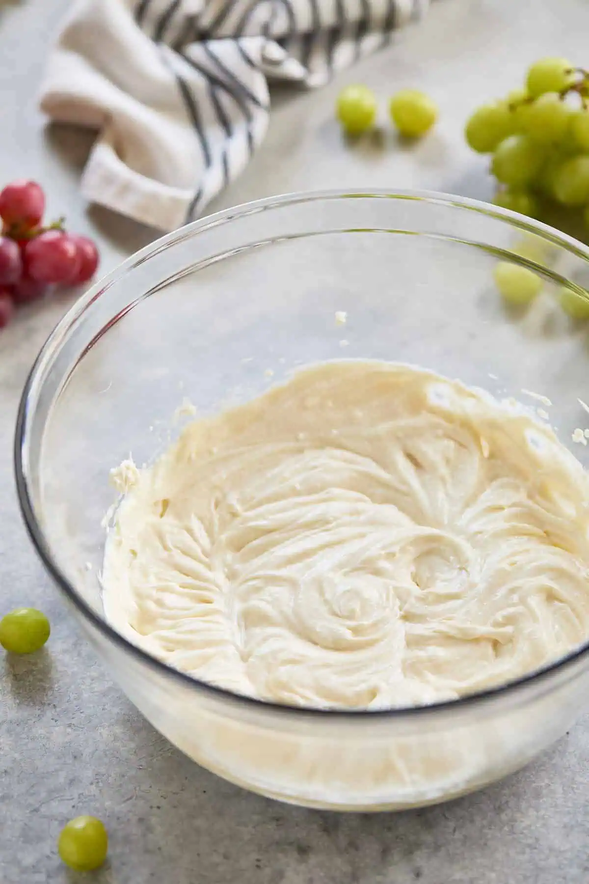 Glass bowl with a smooth, creamy mixture of cream cheese, sour cream, sugar, and vanilla extract.