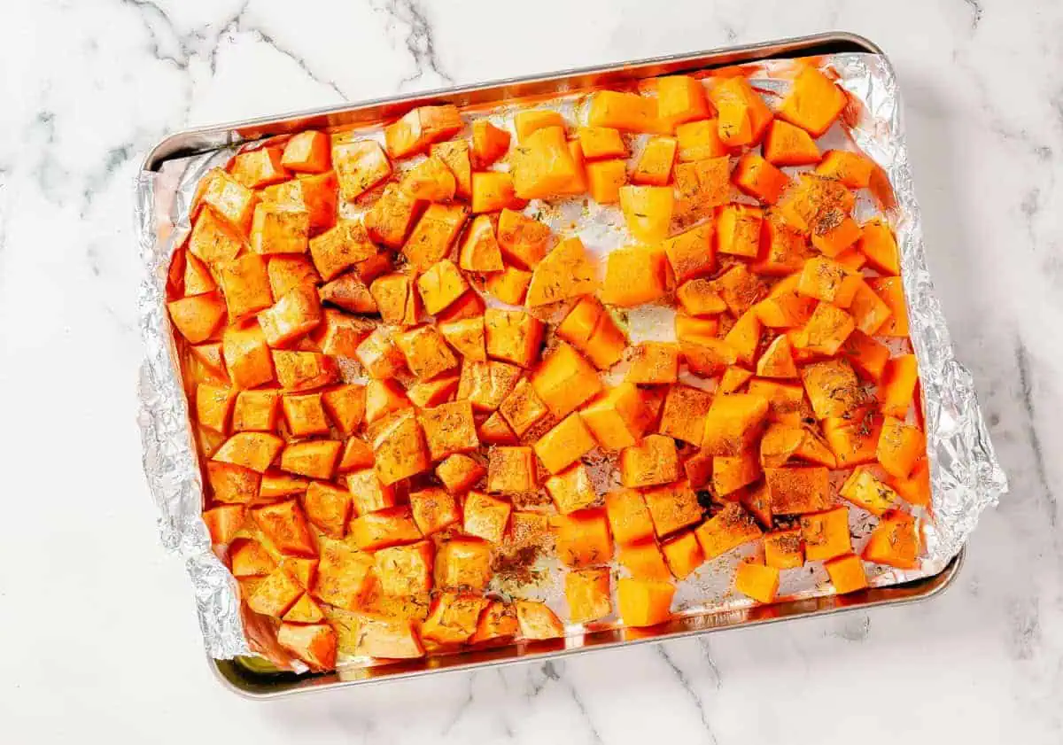 Roasted butternut squash and sweet potatoes on a foil-lined baking sheet, perfectly caramelized and ready for soup.