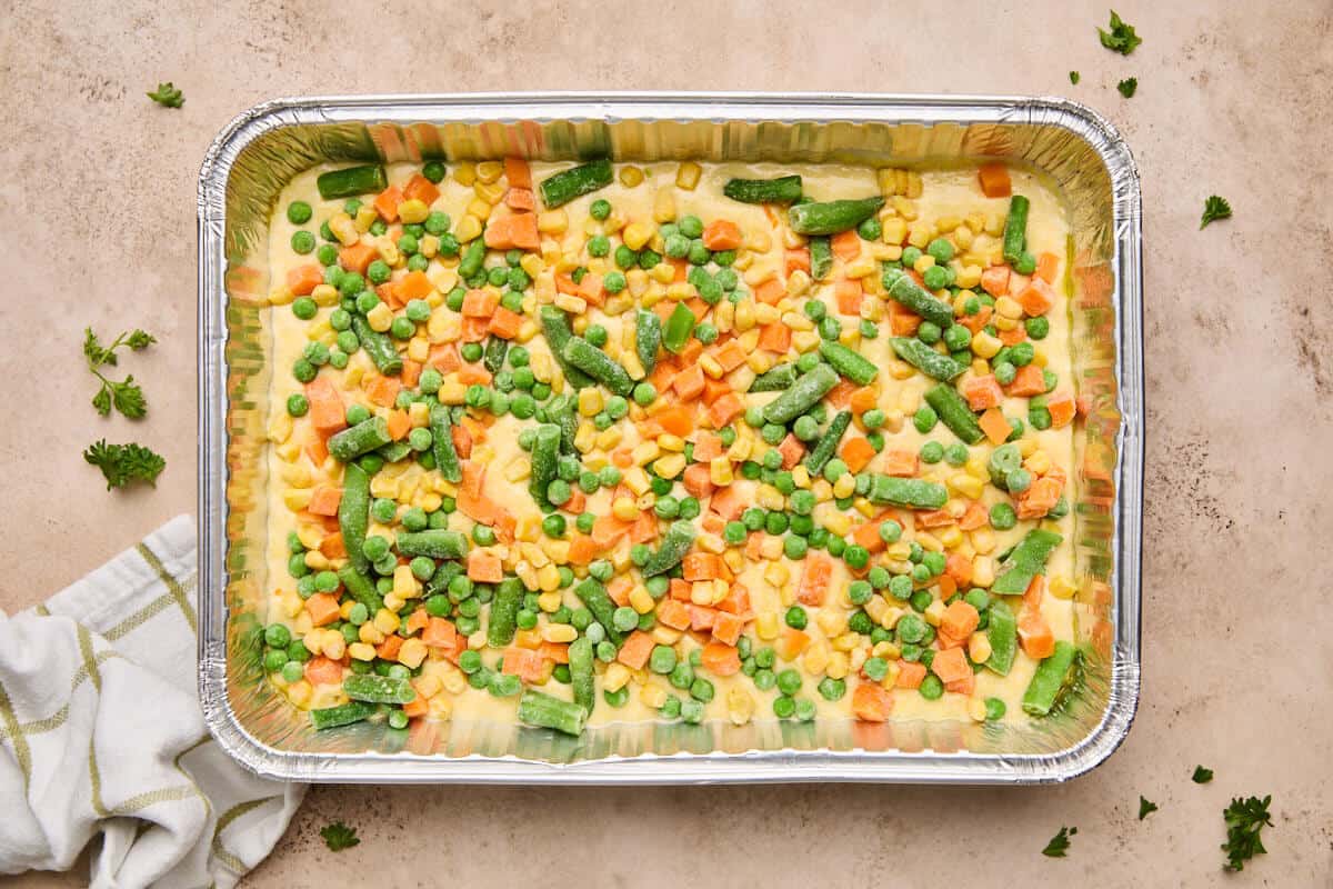 Frozen mixed vegetables sprinkled over the cornbread batter in the baking dish.