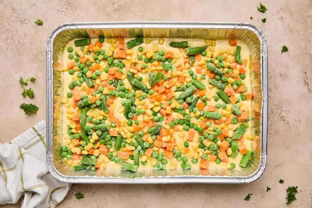 Frozen mixed vegetables sprinkled over the cornbread batter in the baking dish.