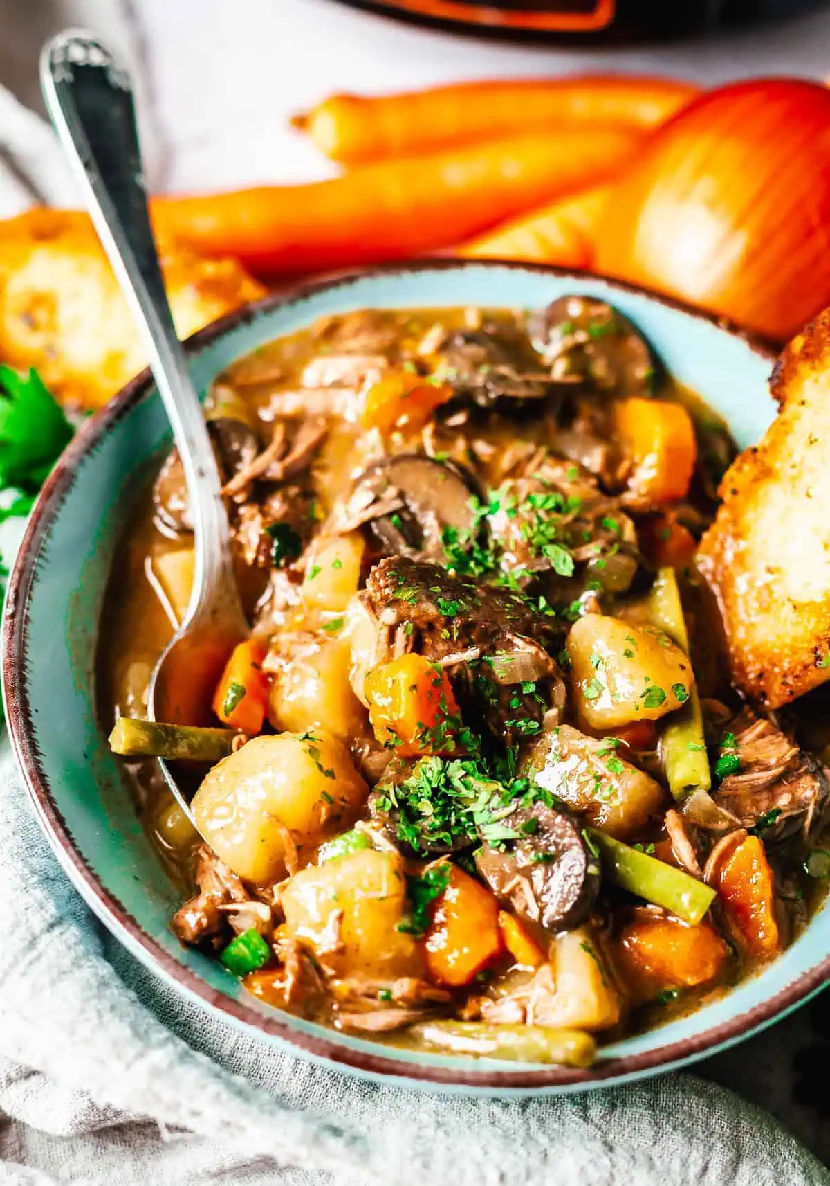 Slow cooker filled with hearty beef stew, brimming with vegetables and tender beef, garnished with parsley.