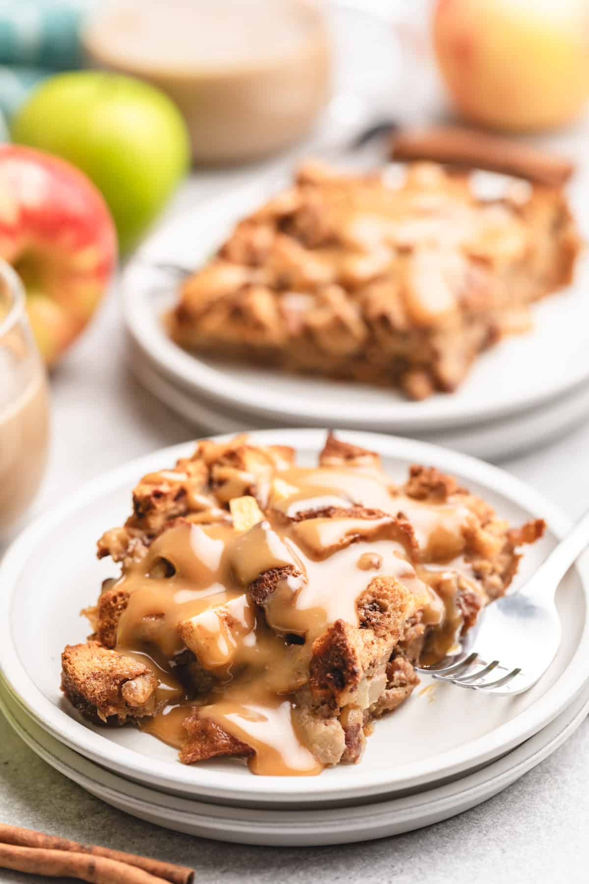 Bread pudding with caramel sauce on a stack of plates.