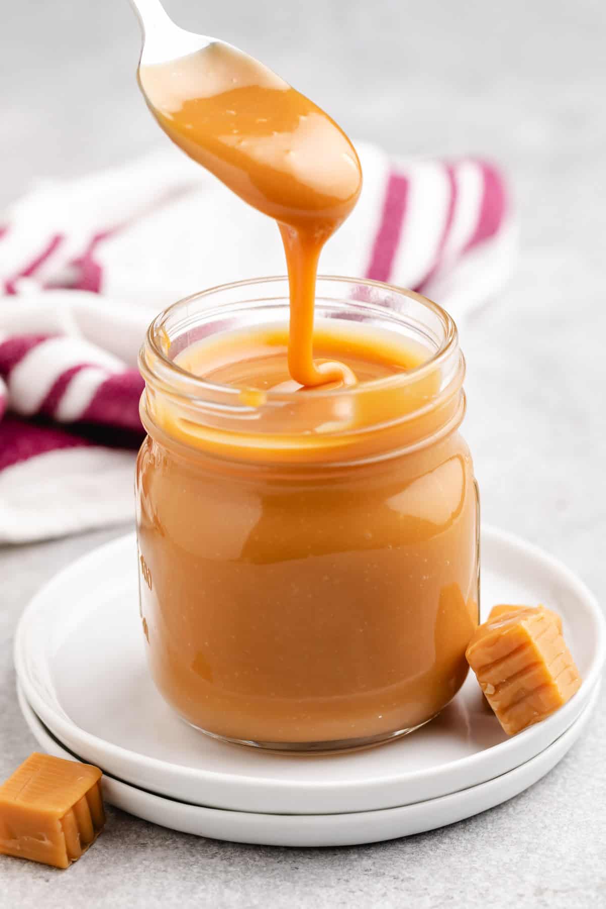 A jar of caramel sauce with a spoon inside.