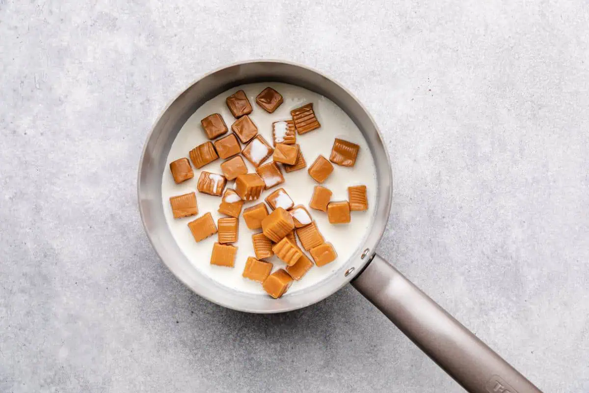 Caramel squares melting in a saucepan of heavy cream.