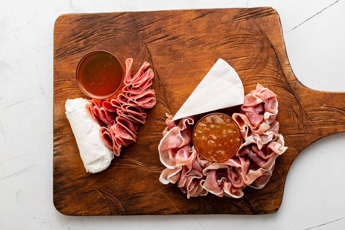 Honey, jam, cheese and meat on a wooden board.