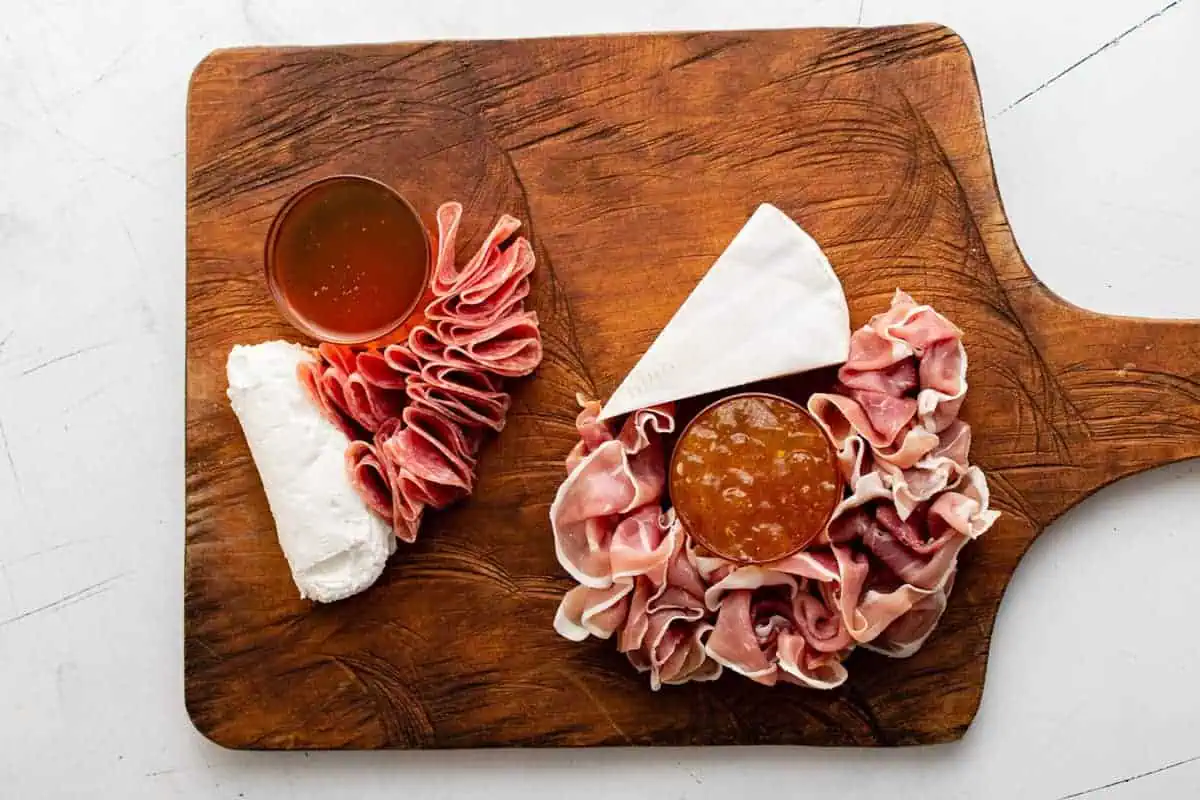 Honey, jam, cheese and meat on a wooden board.