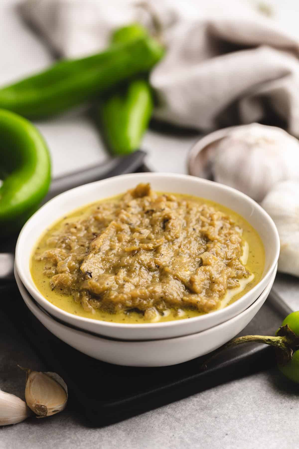 Hatch green chile sauce with a rich and creamy consistency, garnished with garlic cloves, a great topping for New Mexico-inspired recipes.