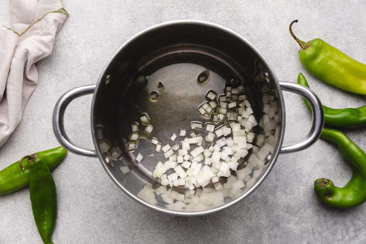 Diced onions saut&eacute;ing in a saucepan, the base for a rich and flavorful hatch green chile sauce recipe.